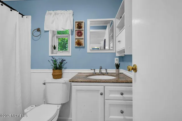 a bathroom with a granite countertop sink and a toilet