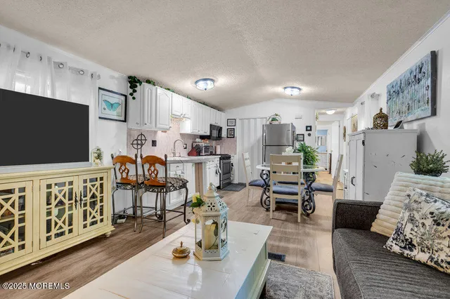 a living room with furniture kitchen view and a flat screen tv