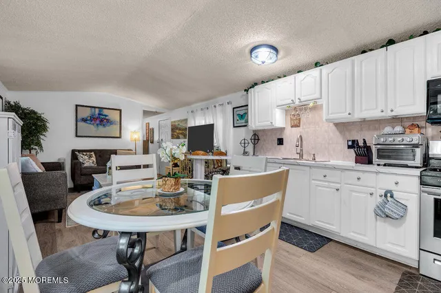 a kitchen with stainless steel appliances kitchen island granite countertop a sink a stove a table and chairs