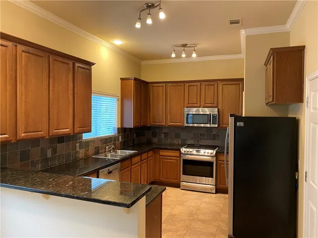 a kitchen with granite countertop a refrigerator a stove a sink and a counter space