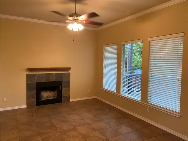 a view of an empty room with window and chandelier fan