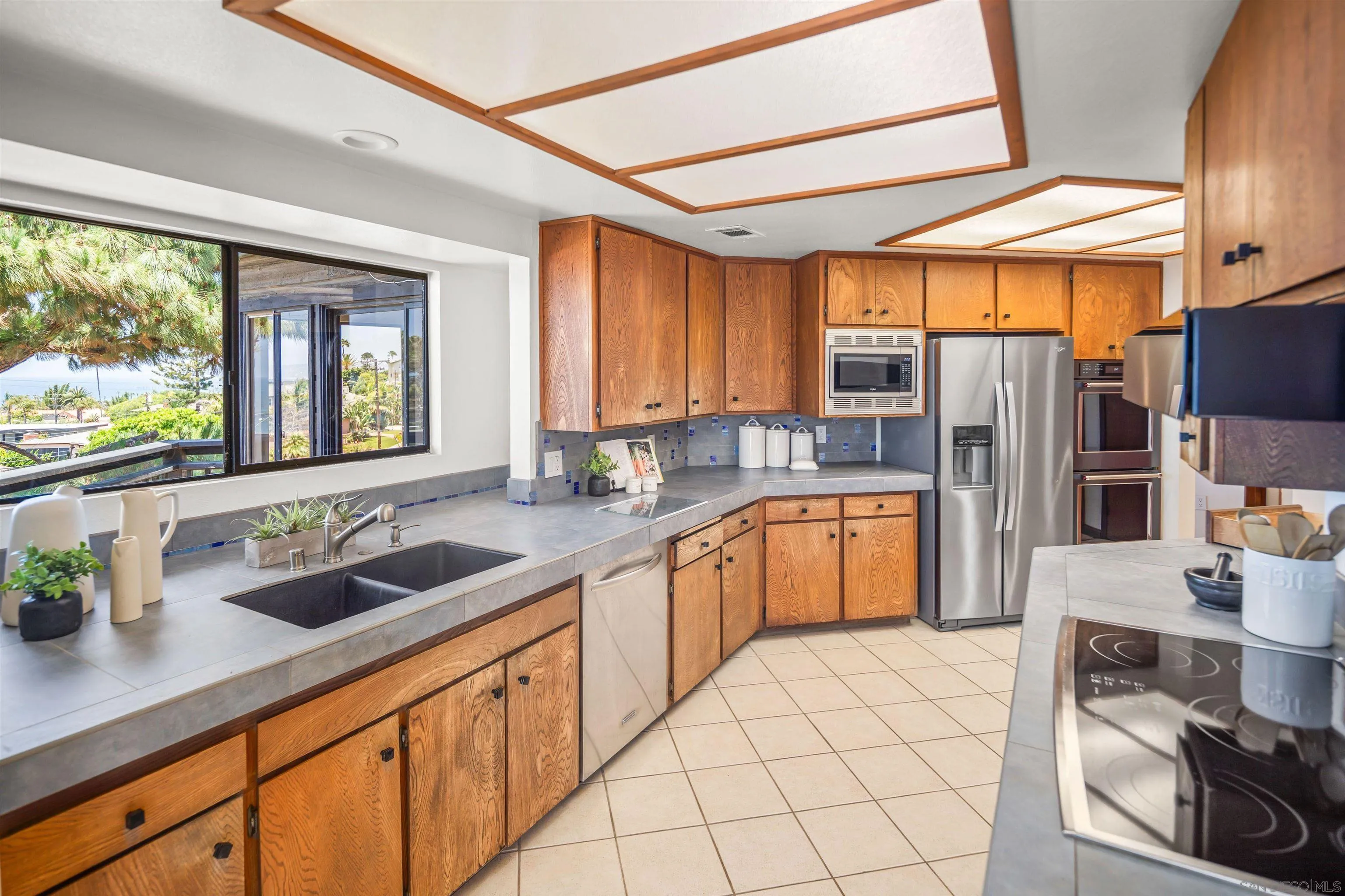 1005 Cornish Drive San Diego, CA 92107 - Photo 18 of 71 a kitchen with stainless steel appliances a sink dishwasher a refrigerator a stove and white cabinets with wooden floor