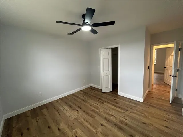 an empty room with wooden floor cabinet and a ceiling fan