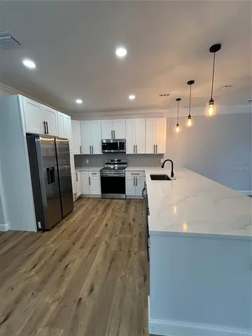 a large kitchen with stainless steel appliances granite countertop a refrigerator a sink a stove and oven