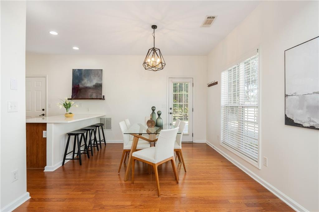 4150 Lake Pass Lane Suwanee, GA 30024 - Photo 16 of 46 a dining room with wooden floor a chandelier a glass table and chairs