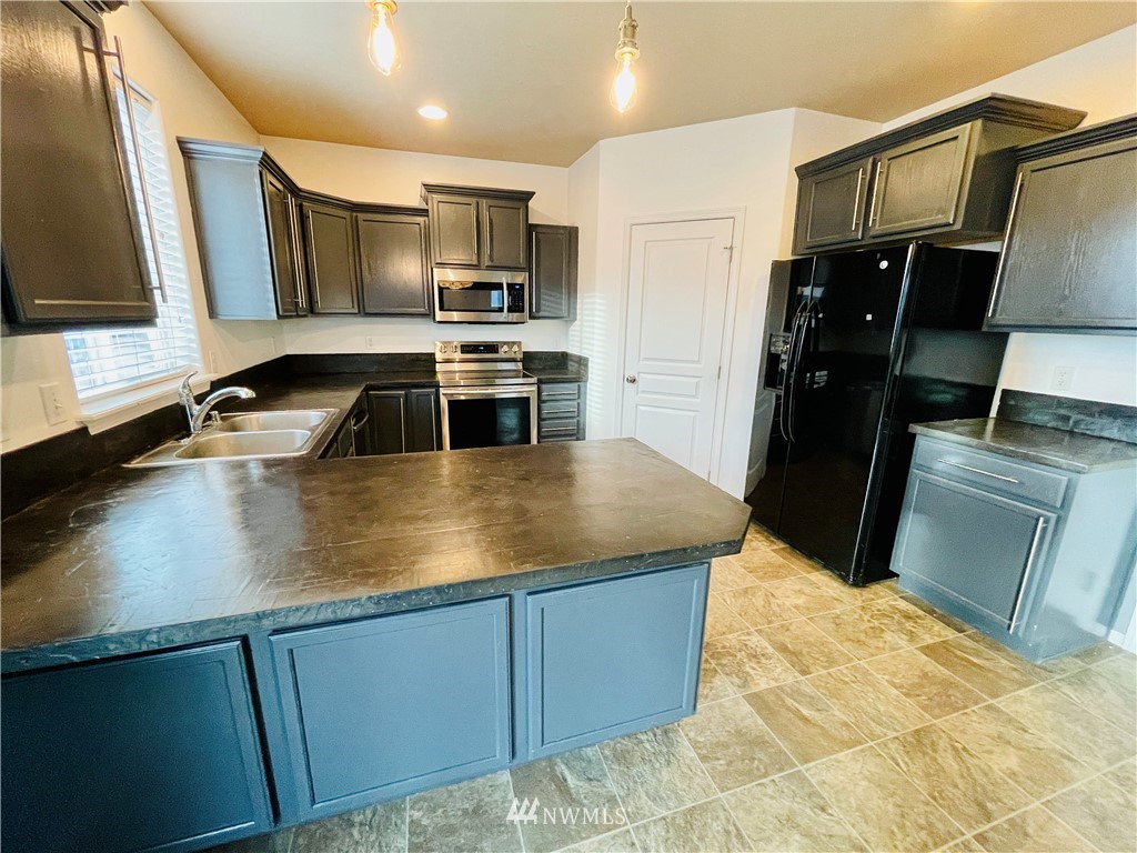 1924 Stevens Street Walla Walla, WA 99362 - Photo 7 of 24 a kitchen with stainless steel appliances a sink a stove top oven a refrigerator and island