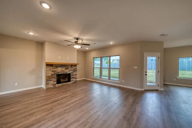 a view of an empty room with wooden floor fireplace and a window
