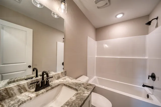 a bathroom with a granite countertop sink and a bathtub