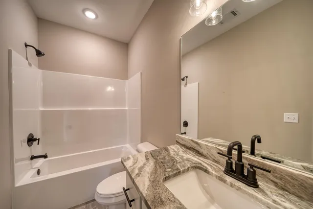 a bathroom with a granite countertop sink a toilet and shower