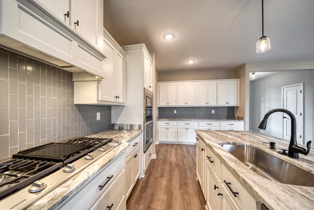 a kitchen with kitchen island granite countertop a sink stainless steel appliances and cabinets