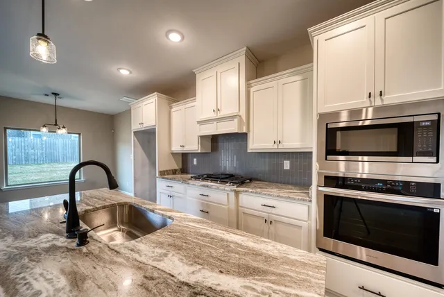 a kitchen with granite countertop a stove a sink and a microwave