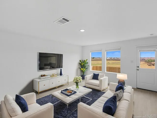 a living room with furniture a flat screen tv and a window