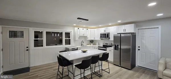 a kitchen with a refrigerator a dining table and chairs