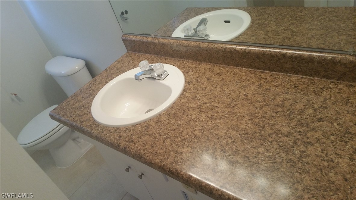 207 Jasmine Road West Lehigh Acres, FL 33936 - Photo 21 of 25 a bathroom with a granite countertop sink and a mirror