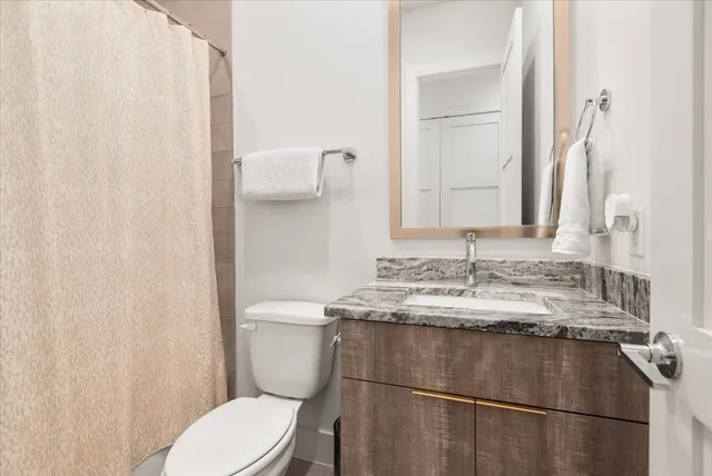 a bathroom with a granite countertop sink toilet and mirror