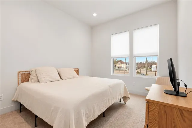 a bedroom with a bed a flat screen tv and a large window