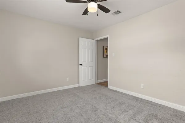 an empty room with a ceiling fan and carpet