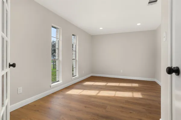 an empty room with wooden floor and windows