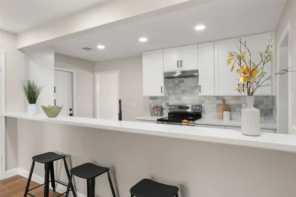 a kitchen with kitchen island a stove top oven a sink and cabinets