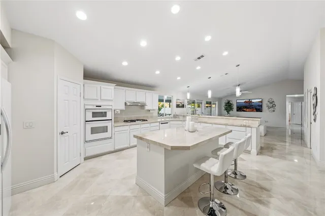 a large white kitchen with a large island in the center