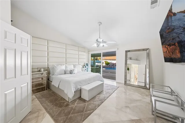 a spacious bedroom with a bed a dresser and a large window