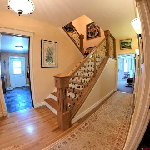 a view of a hallway with wooden floor staircase and a living room