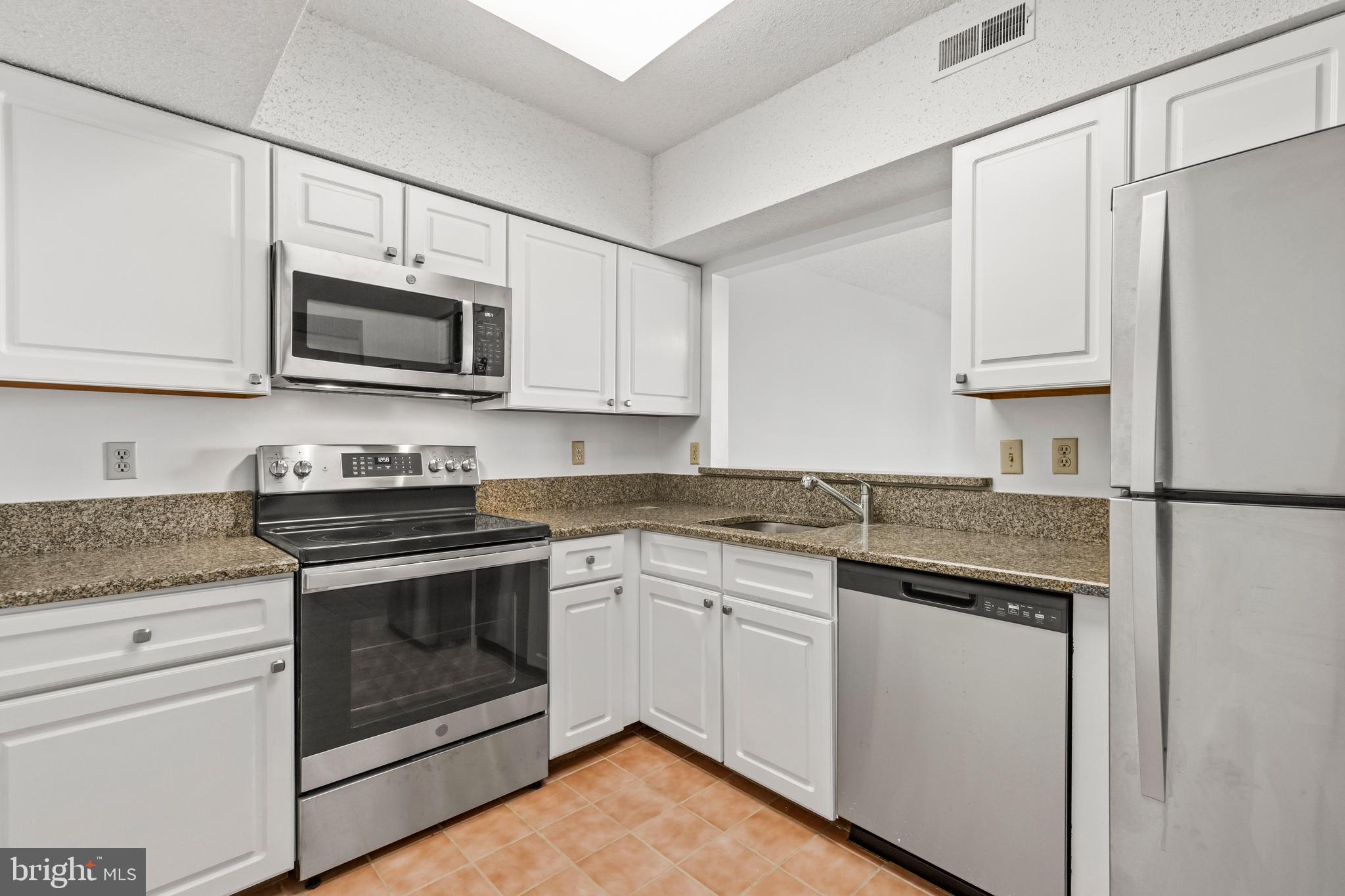 a kitchen with cabinets stainless steel appliances a sink and a microwave