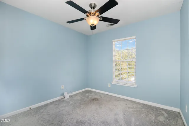 an empty room with a window and a ceiling fan