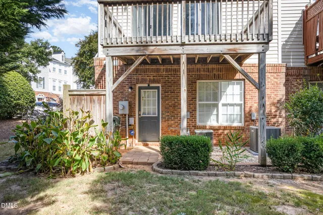 a view of a house with brick walls and a yard with plants