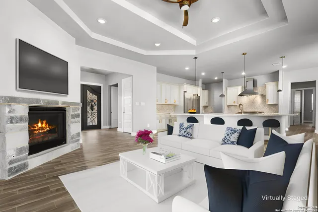 a very nice looking living room with stainless steel appliances furniture a fireplace and a flat screen tv