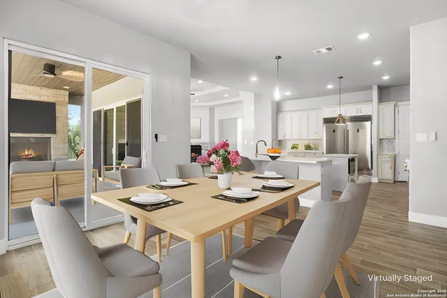 a dining room with stainless steel appliances kitchen island granite countertop a dining table chairs and a refrigerator