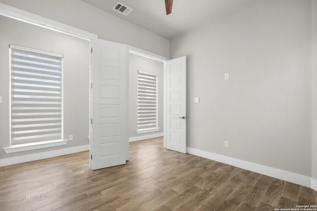 an empty room with wooden floor and windows