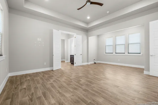 an empty room with windows and ceiling fan