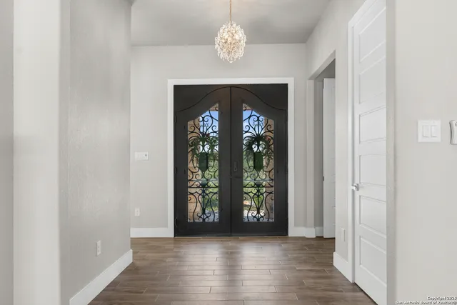 an empty room with wooden floor chandelier and windows