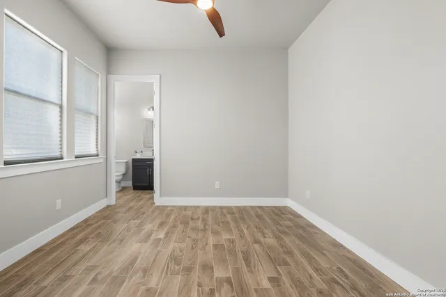 an empty room with wooden floor and windows