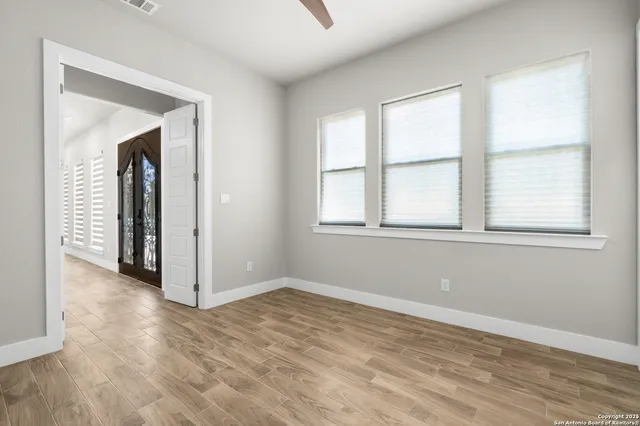 an empty room with wooden floor and windows