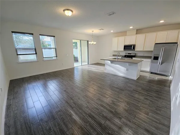 a view of kitchen with kitchen island wooden floors and stainless steel appliances