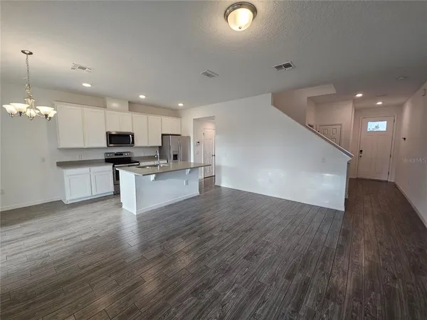 an open kitchen with kitchen island a sink wooden floor and stainless steel appliances