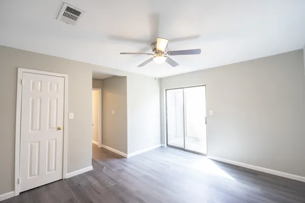 an empty room with wooden floor and ceiling fan