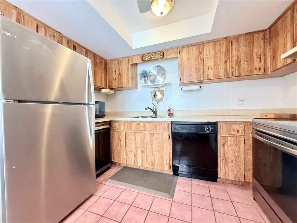 9000 Commodore Drive, Unit 302 Seminole, FL 33776 - Photo 9 of 21 a kitchen with a refrigerator a stove a washer and dryer with wooden floor