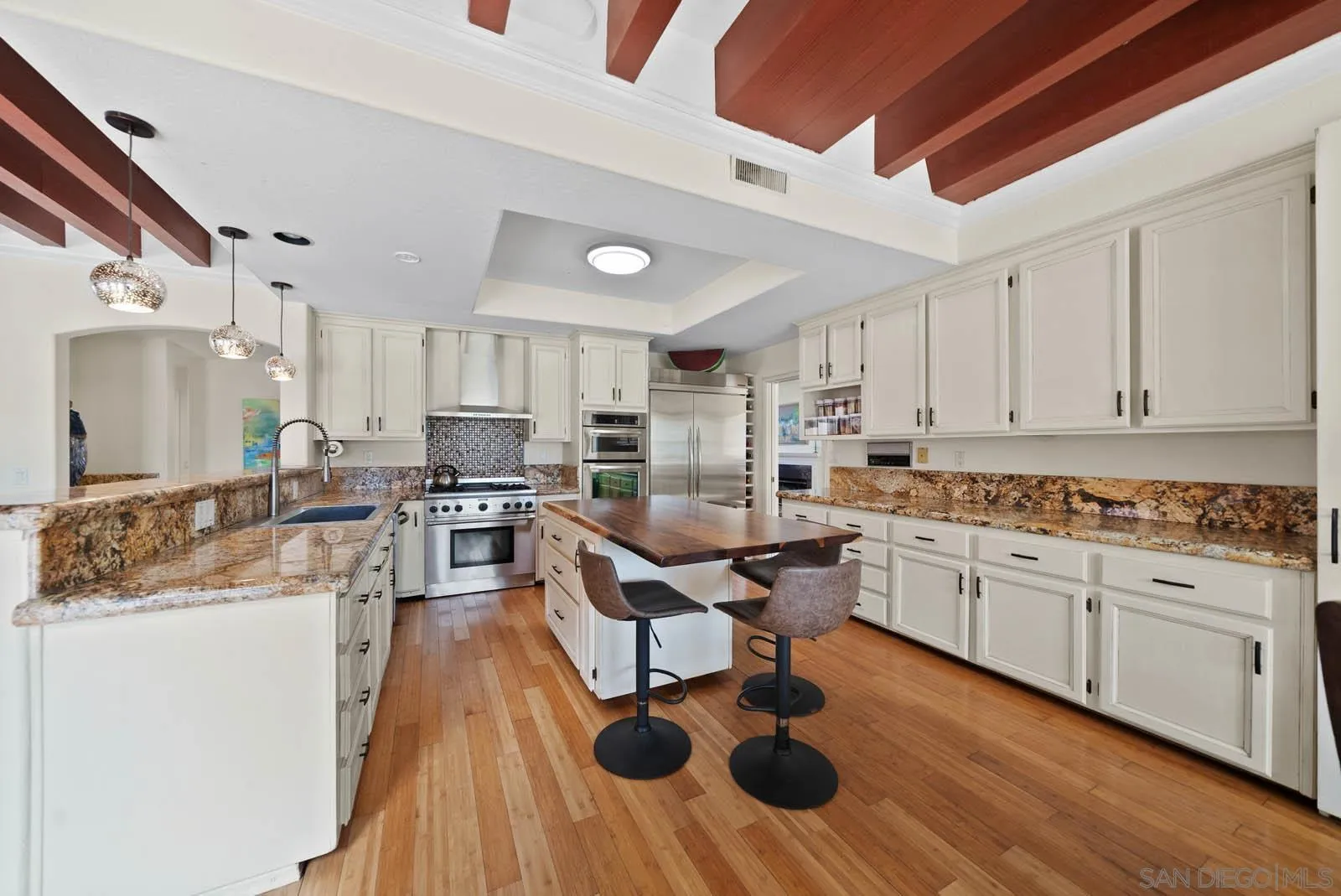 308 Crestview Drive Bonita, CA 91902 - Photo 18 of 37 a kitchen with stainless steel appliances kitchen island granite countertop a stove top oven a sink a dining table and chairs with wooden floor
