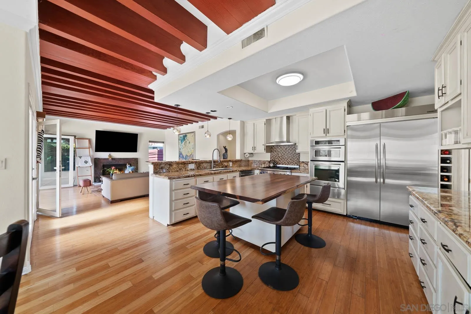308 Crestview Drive Bonita, CA 91902 - Photo 19 of 37 a kitchen with stainless steel appliances kitchen island granite countertop a table chairs in it and wooden floors