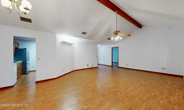 a view of an empty room with wooden floor