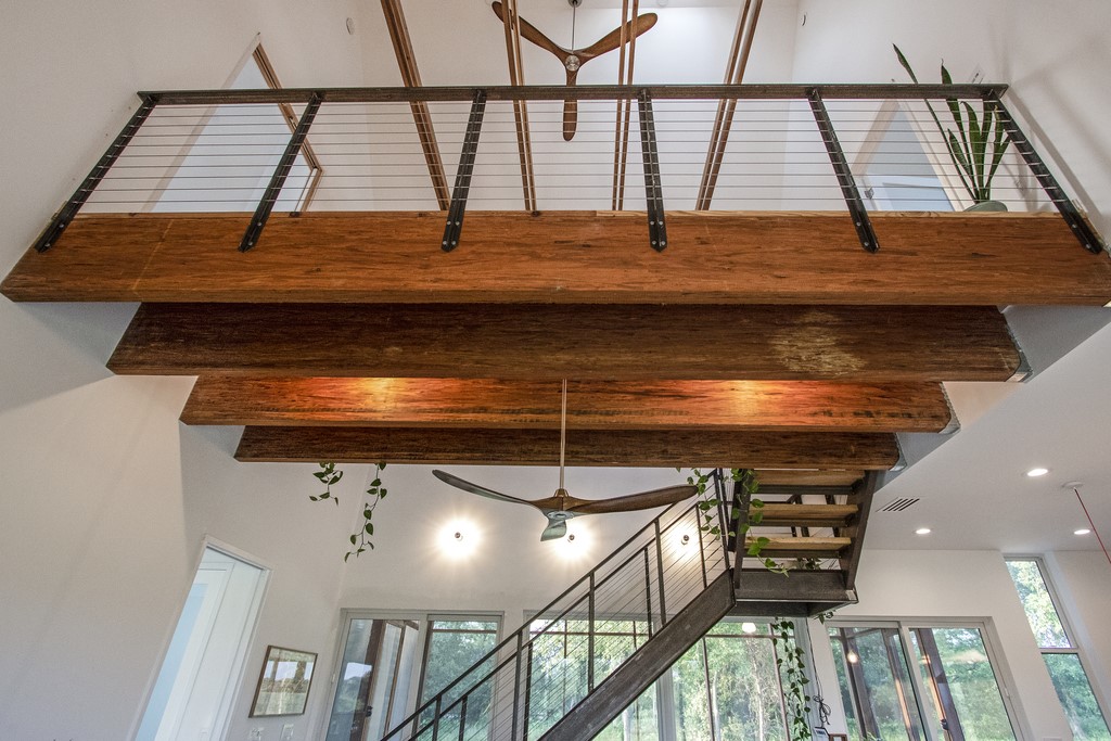 534 Old McDade Road Elgin, TX 78621 - Photo 23 of 40 Catwalk between upstairs suites is a stunning architectural feature. Large wooden beams bring warmth and incredible design elements to the downstairs living room.