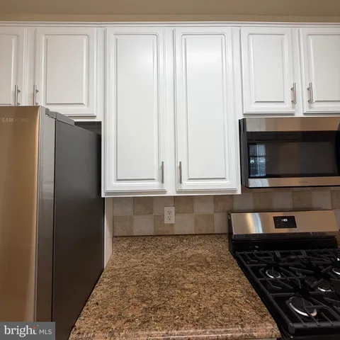 a kitchen with granite countertop a stove and a refrigerator
