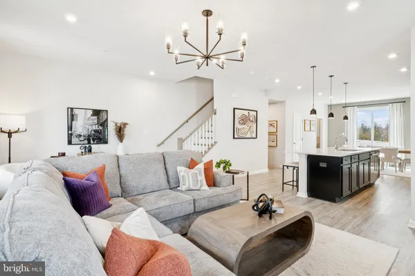 a living room with furniture kitchen view and a wooden floor