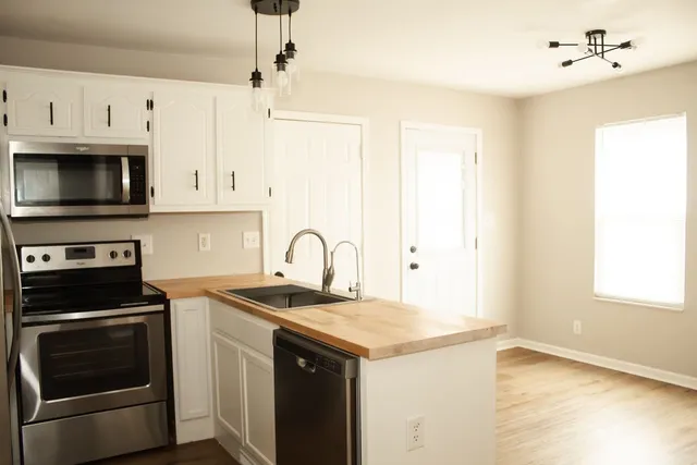a kitchen with granite countertop a sink stainless steel appliances and white cabinets