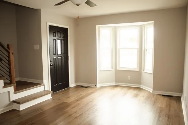 an empty room with wooden floor and windows