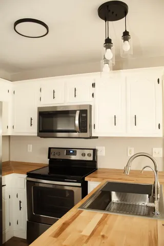 a kitchen with stainless steel appliances granite countertop a sink a stove and a microwave