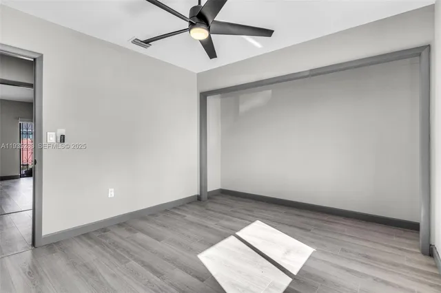 an empty room with wooden floor and a ceiling fan